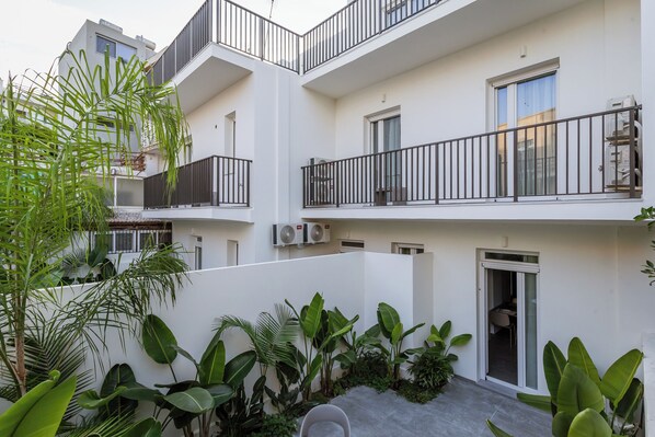 A multi-story residential building with balconies, air conditioning units, and lush greenery.