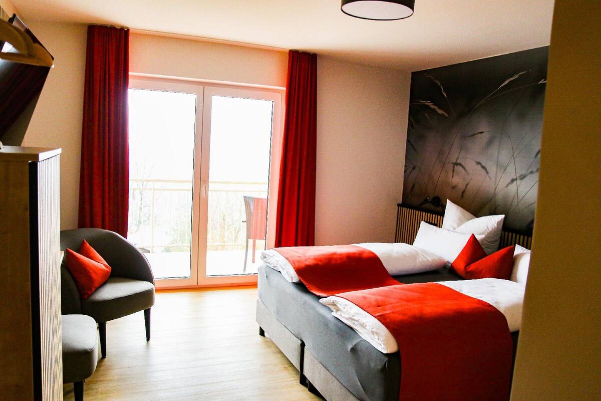 A hotel room with a bed, a chair, and a large window.