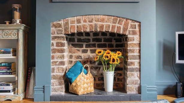 A brick fireplace with a vase of sunflowers and a woven bag. - Family Stay | By Sefton Park & Lark Lane | Parking (Liverpool)