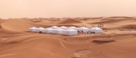 A row of white tents in a desert landscape.