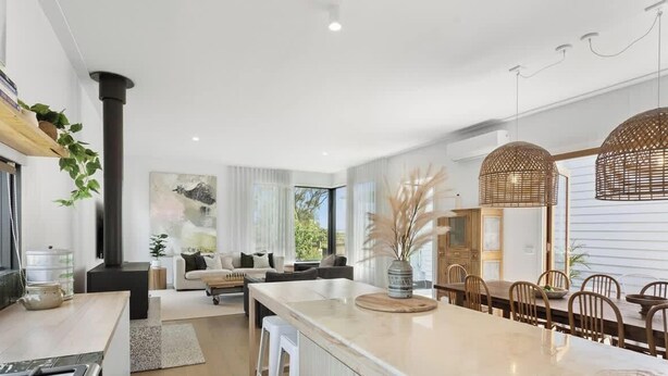 A modern kitchen with a central island, a dining area with wooden chairs, and a living space with a sofa and a coffee table.