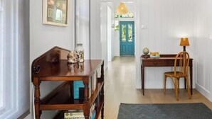 A hallway with a wooden bench, a table with a lamp, and a door with a blue frame.