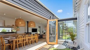 An open-plan living area with a dining table and chairs, a kitchen area, and a glass door leading to an outdoor patio.