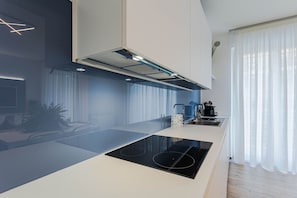 A modern kitchen with a central island, built-in appliances, and a large window with sheer curtains. - Affittacamere Incanto a Mare Apartment by Wonderful Italy (Polignano a Mare)