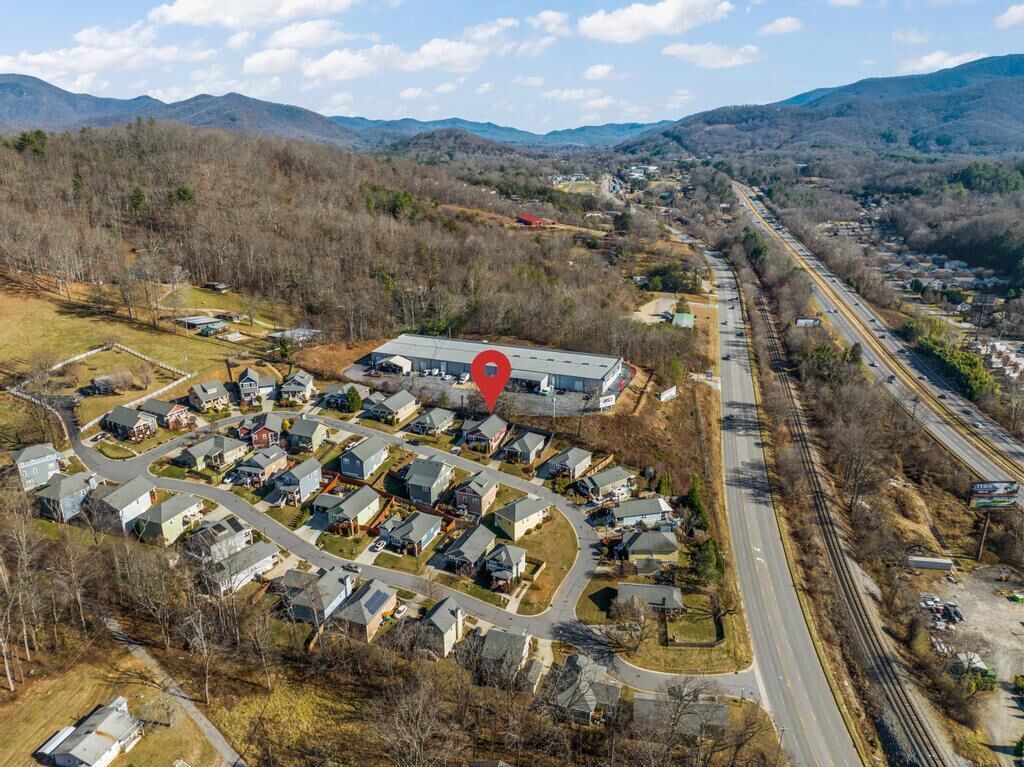 An aerial view of a residential area with houses, a road, and a railway track.