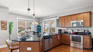 A modern kitchen with wooden cabinets, stainless steel appliances, and a central island. - Mountain Views, Game Room, Hot Tub –Close to Downtown (Asheville)