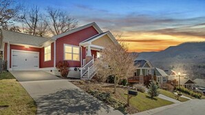 A two-story house with a red exterior, a front porch, and a driveway leading to a garage. - Mountain Views, Game Room, Hot Tub –Close to Downtown (Asheville)