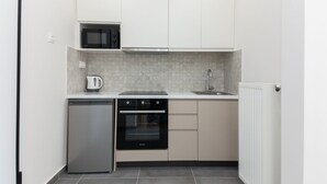 Eine kompakte Küche mit Mikrowelle, Wasserkocher, Geschirrspüler und eingebautem Backofen.