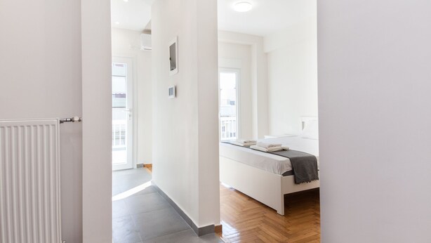 Ein modernes Schlafzimmer mit Bett, Nachttisch und Fenster.