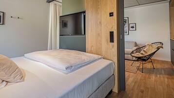 A modern bedroom with a bed, a wooden wall, a TV, and a chair.