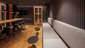 A modern interior with a wooden dining table, black stools, a grey sofa, and a large window with curtains.