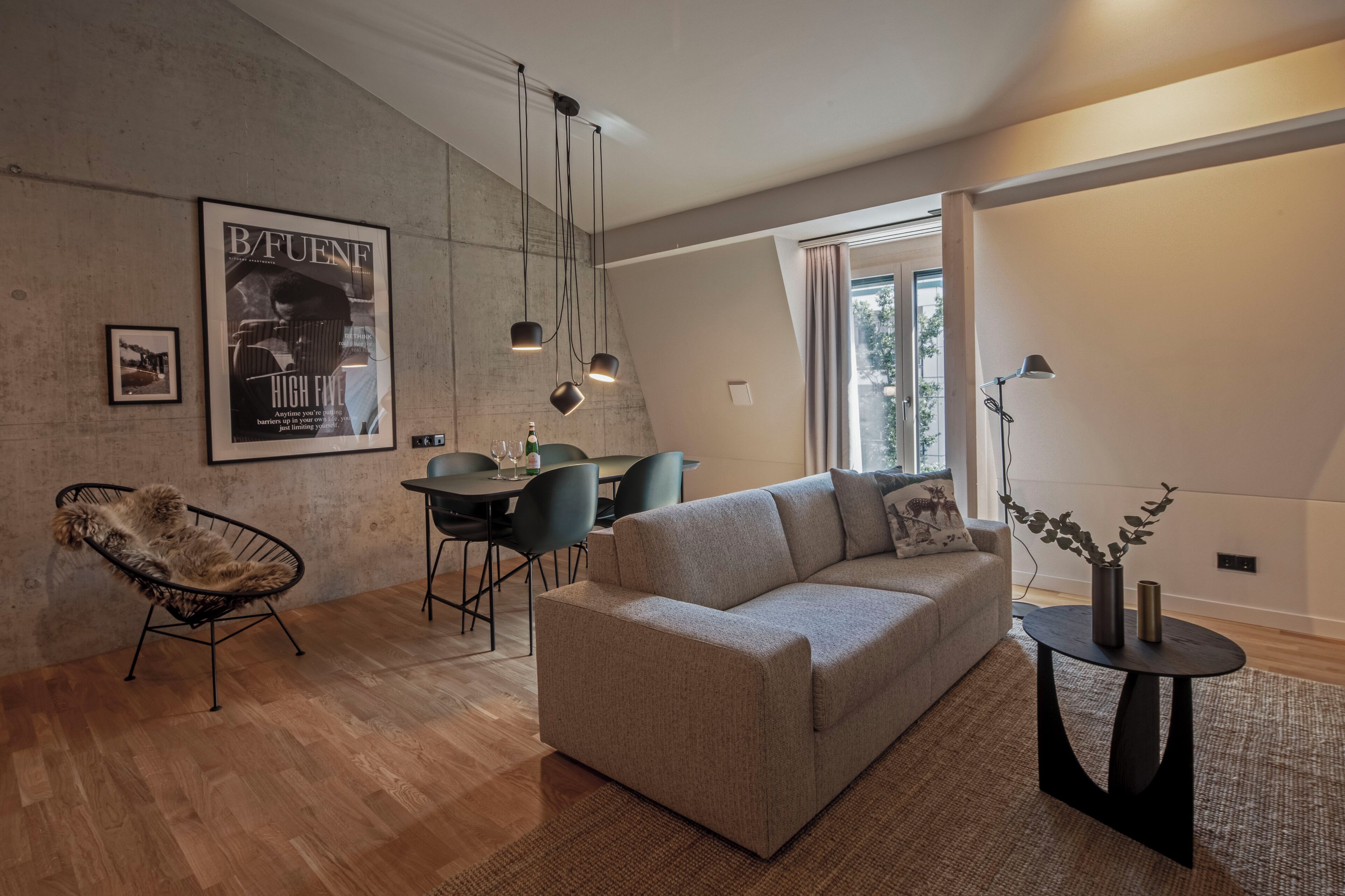 Una sala moderna con un sofá, un sillón, una mesa de comedor y un cartel en la pared.