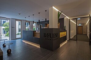 A modern reception area with a reception desk labeled "B/FUENF APARTMENTS," large windows, and a view of the outdoors. - B5 Apartments (Karlsruhe)