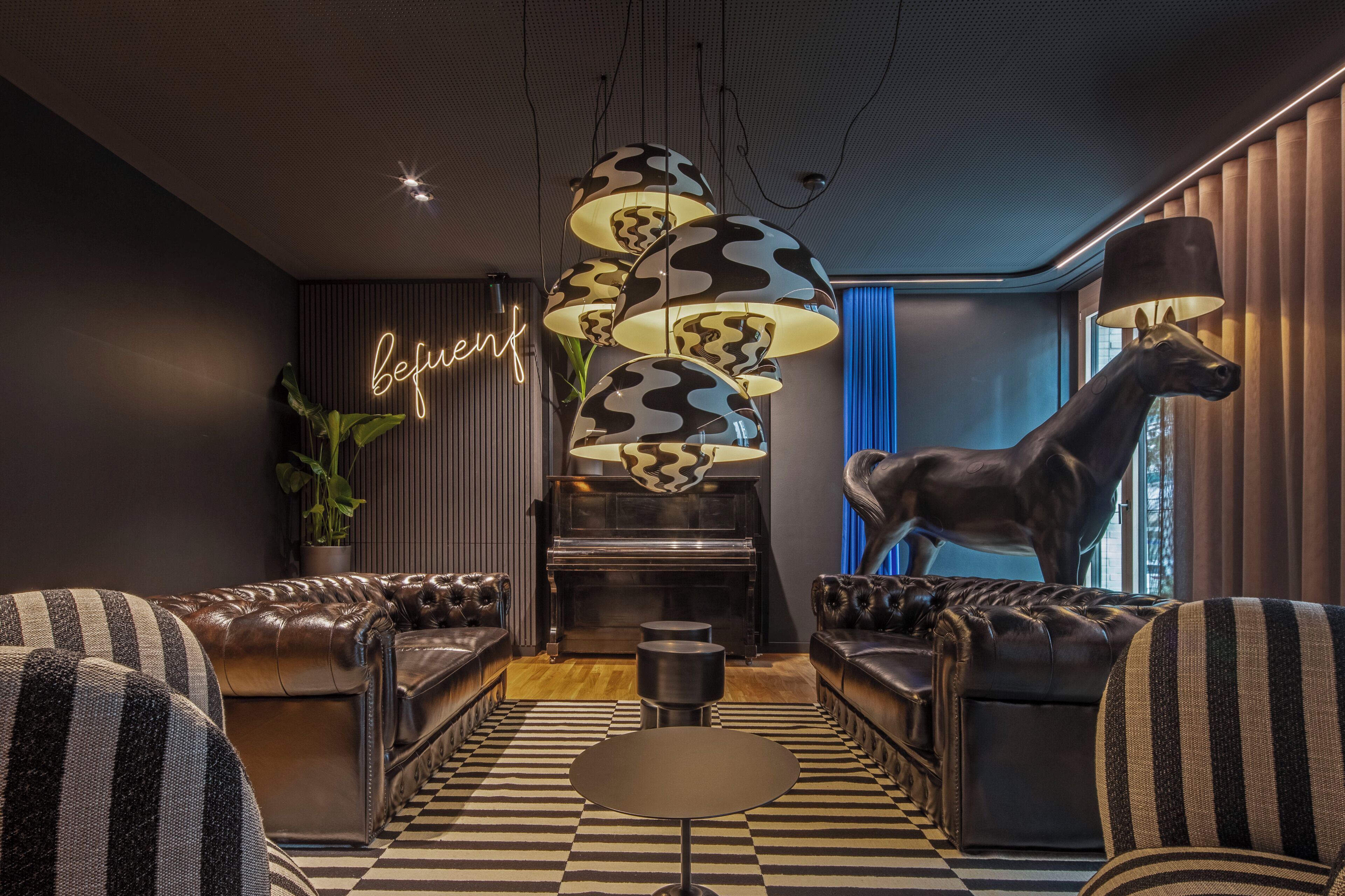 A modern living room with a piano, striped sofas, a checkered floor, and a neon sign.