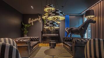 A modern living room with a piano, striped sofas, a checkered floor, and a neon sign.