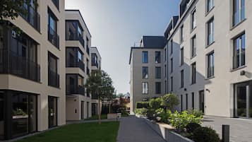Ein moderner Wohnkomplex mit Innenhof, Balkone, großen Fenstern und einem gepflegten Rasen.