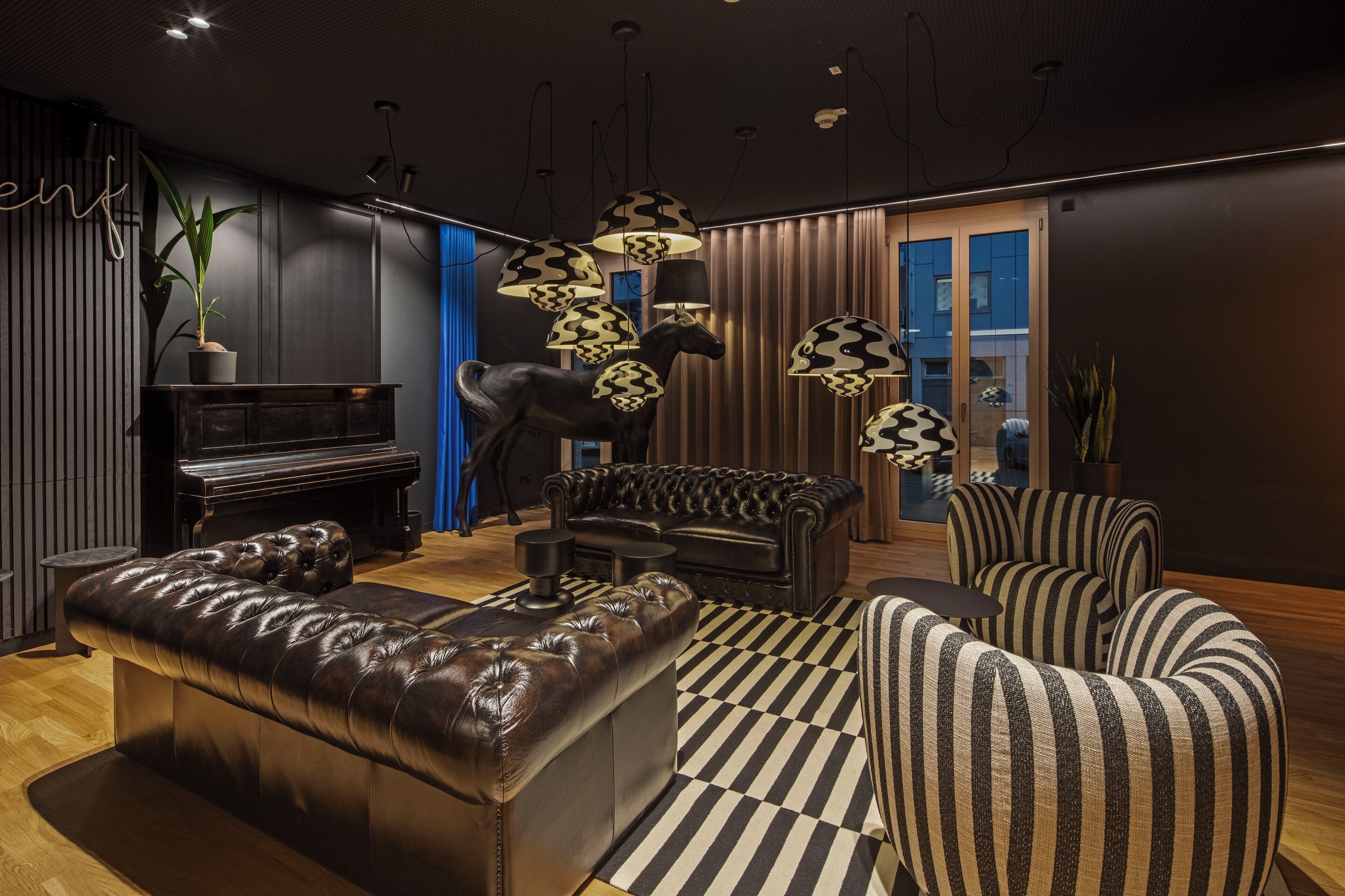 A modern living room with a piano, leather sofas, and patterned armchairs.