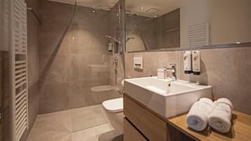 Une salle de bain moderne avec une douche à parois de verre, un lavabo blanc et un meuble-lavabo en bois.