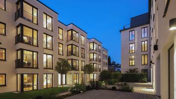 A modern apartment building with multiple balconies, large windows, and a well-lit courtyard.