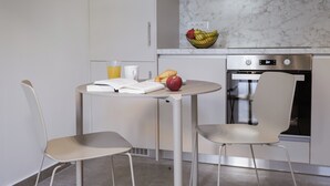 Una cocina moderna con salpicadero de mármol, horno de acero inoxidable y una mesa de comedor con sillas.