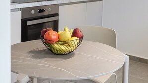 Una cocina moderna con salpicadero de mármol, electrodomésticos de acero inoxidable y un comedor con mesa y sillas.