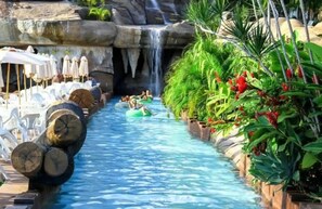 A water slide with people on it, surrounded by plants and a waterfall. - Spazzio DiRoma com Parque incluso (Caldas Novas)