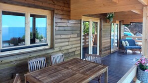 A wooden cabin with a dining area, large windows, and a view of the sea. - Pico Terrace (Madalena)