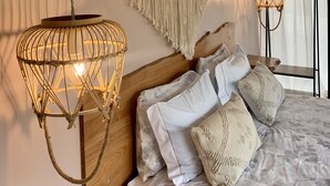 A bedroom with a wooden headboard, a macrame wall hanging, and two hanging lamps. - Pico Terrace (Madalena)
