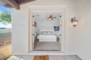 A bedroom with a bunk bed, a ceiling fan, and a wall-mounted light fixture.