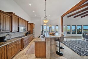 Une cuisine spacieuse avec des meubles en bois, un grand îlot central et des luminaires suspendus.