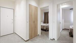 Une chambre d’hôtel avec un lit, une armoire et une salle de bain, visibles à travers une porte ouverte.