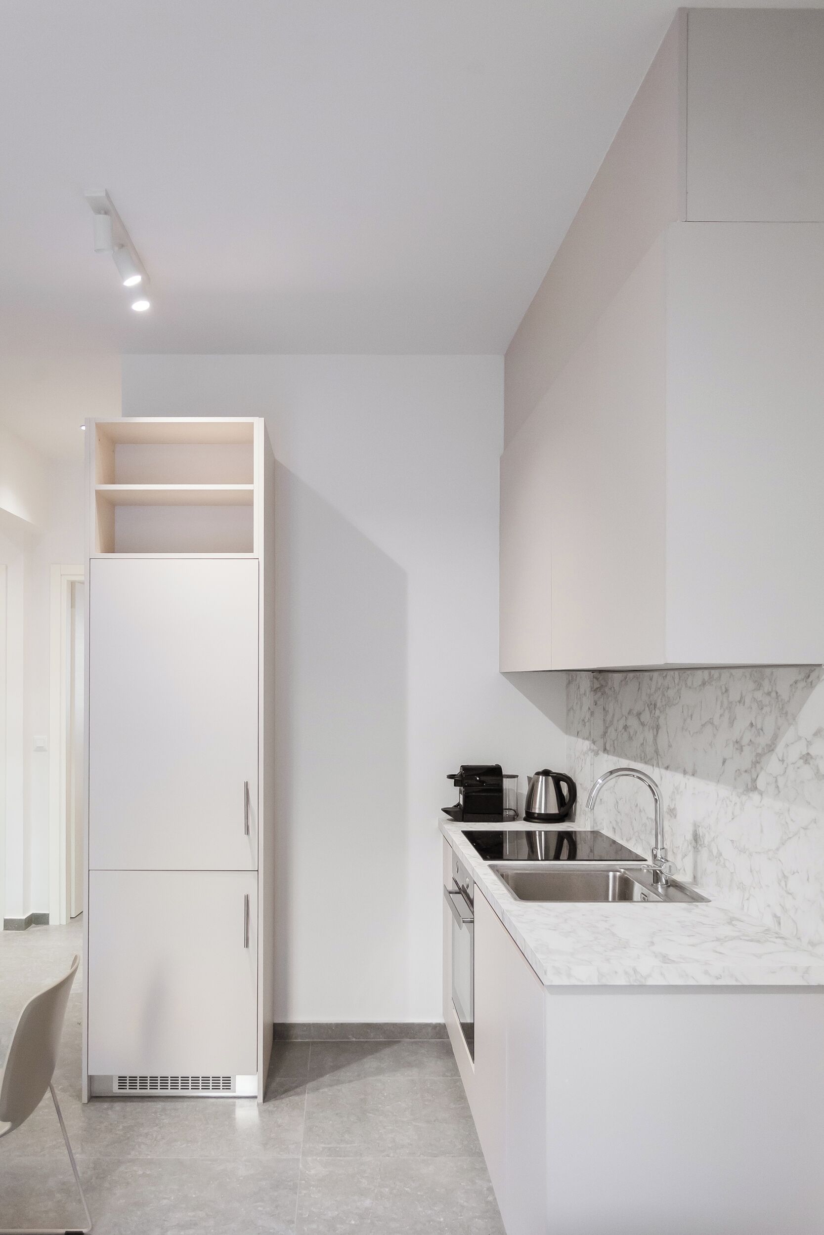 Una cucina moderna con mobili bianchi, un piano di lavoro in marmo e un forno integrato.
