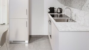 Une cuisine moderne avec des meubles blancs, un plan de travail en marbre et un four encastré.