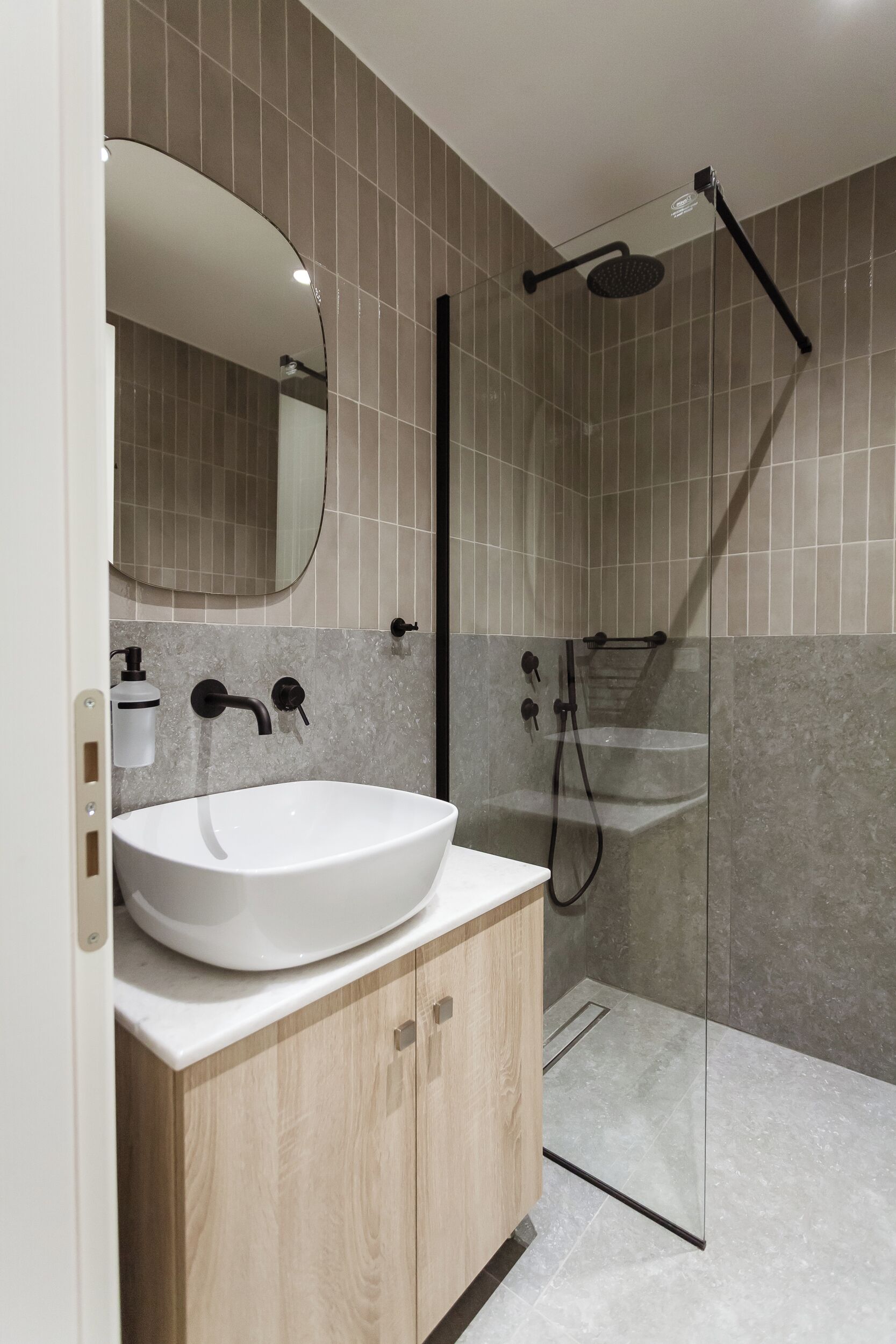 Une salle de bain moderne avec un lavabo blanc, un miroir et un espace douche.