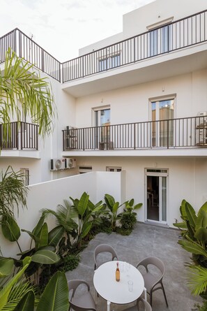 Un edificio residenziale a più livelli con balconi, posti a sedere all'aperto e vegetazione rigogliosa.