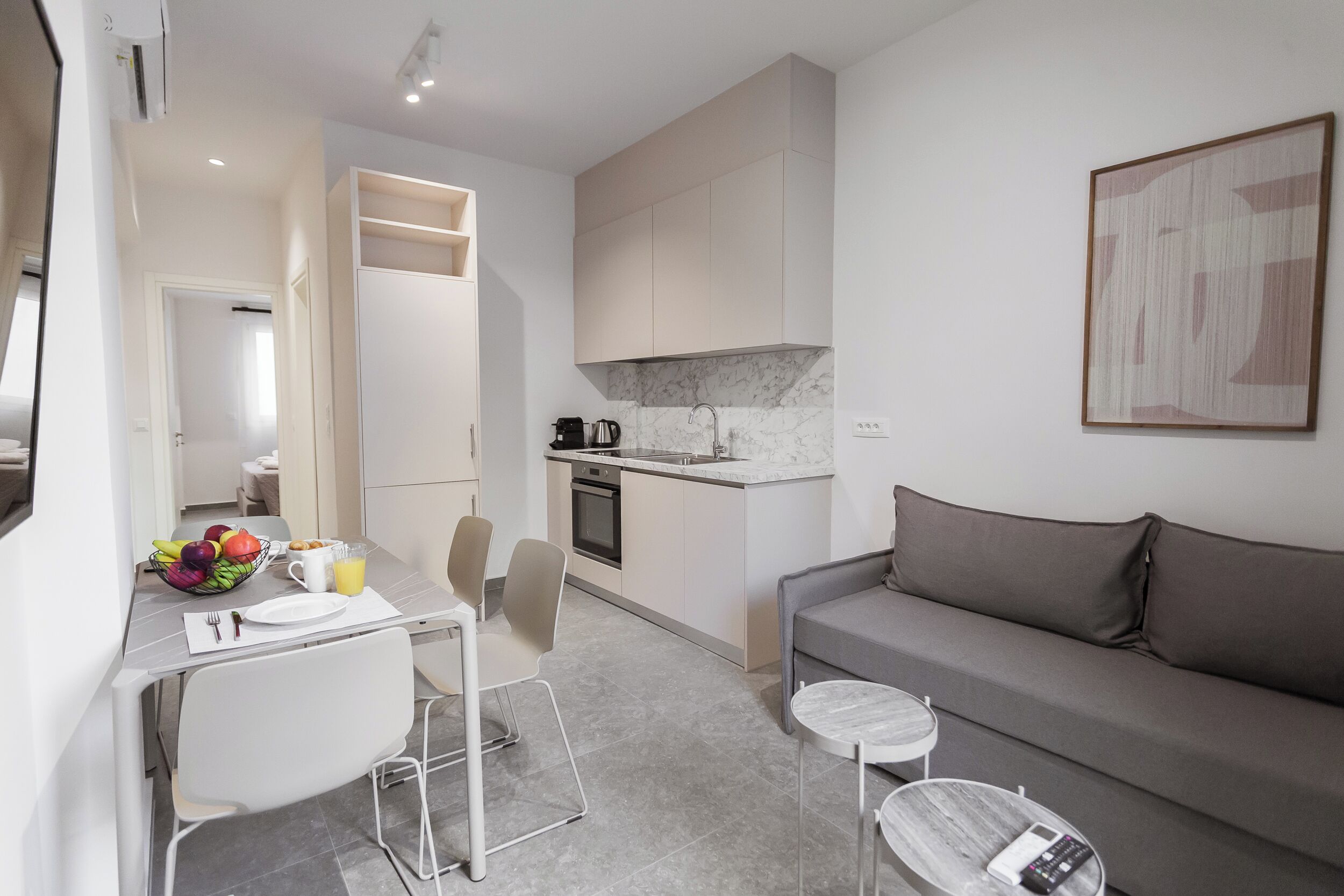 Een moderne keuken met een marmeren aanrecht, een eethoek met een tafel en stoelen, en een grijze bank.
