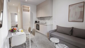 Une cuisine moderne avec un plan de travail en marbre, un coin repas avec une table et des chaises, et un canapé gris.