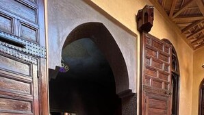 Et traditionelt marokkansk riad med trædøre, en kegleformet lygt og en seng med sengegavl.