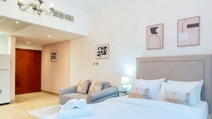 Ein modernes Hotelzimmer mit einem großen Bett, einer Couch, einem Schreibtisch und einer Chandelüster.