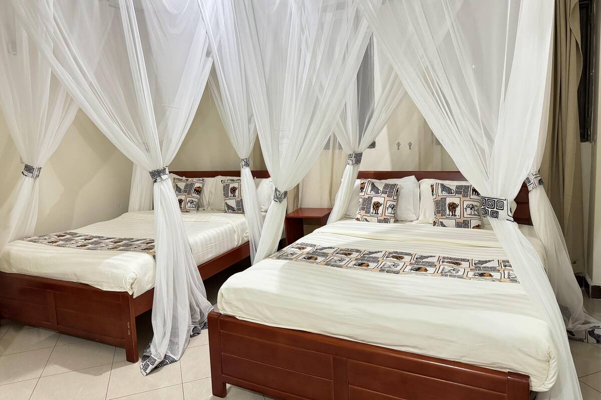 A room with two beds, each with a canopy bedspread and matching pillows.