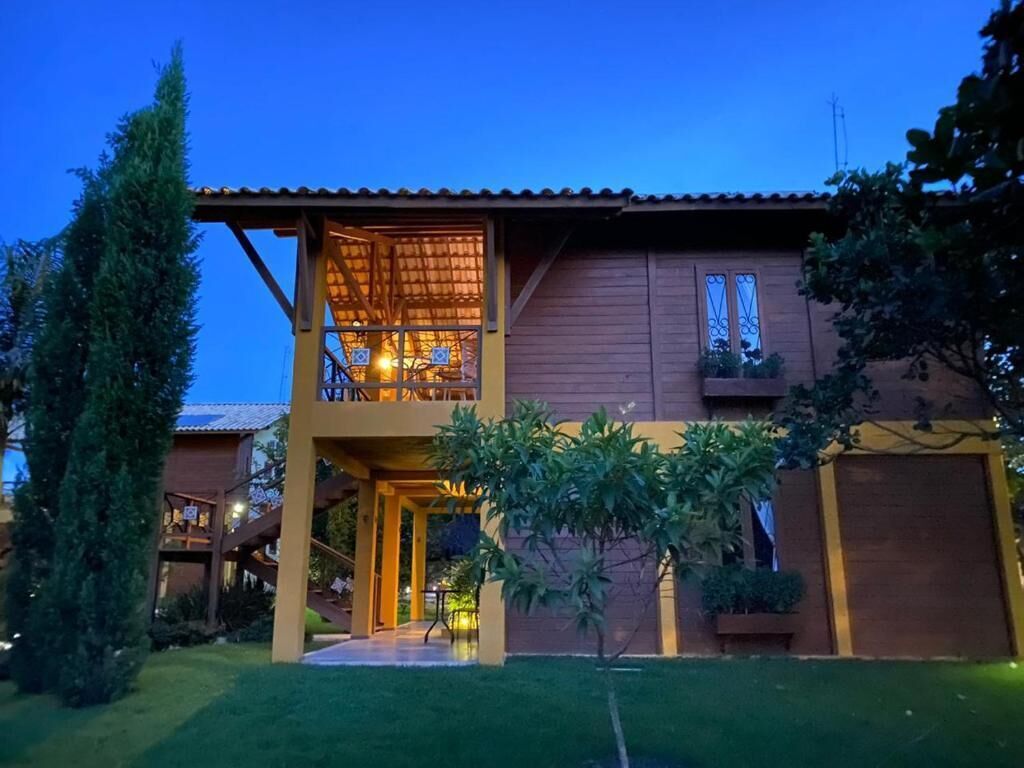 Una casa de madera de dos pisos con un balcón, un césped cuidado y un cielo despejado.