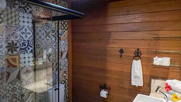 Une salle de bain avec un plafond en bois, une cabine de douche en verre, des toilettes, un lavabo avec un miroir et un porte-serviettes.