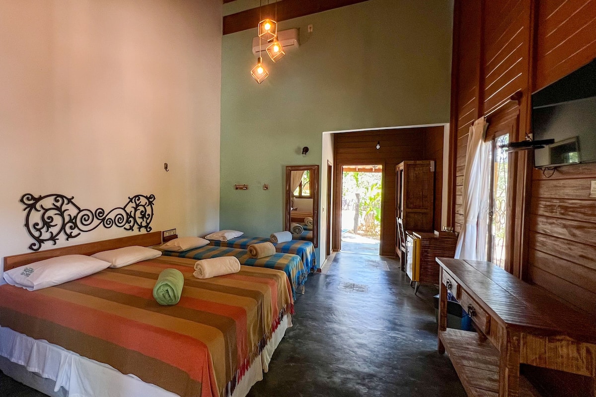 A hotel room with two beds, a wooden headboard, a telephone, and a wooden bench.