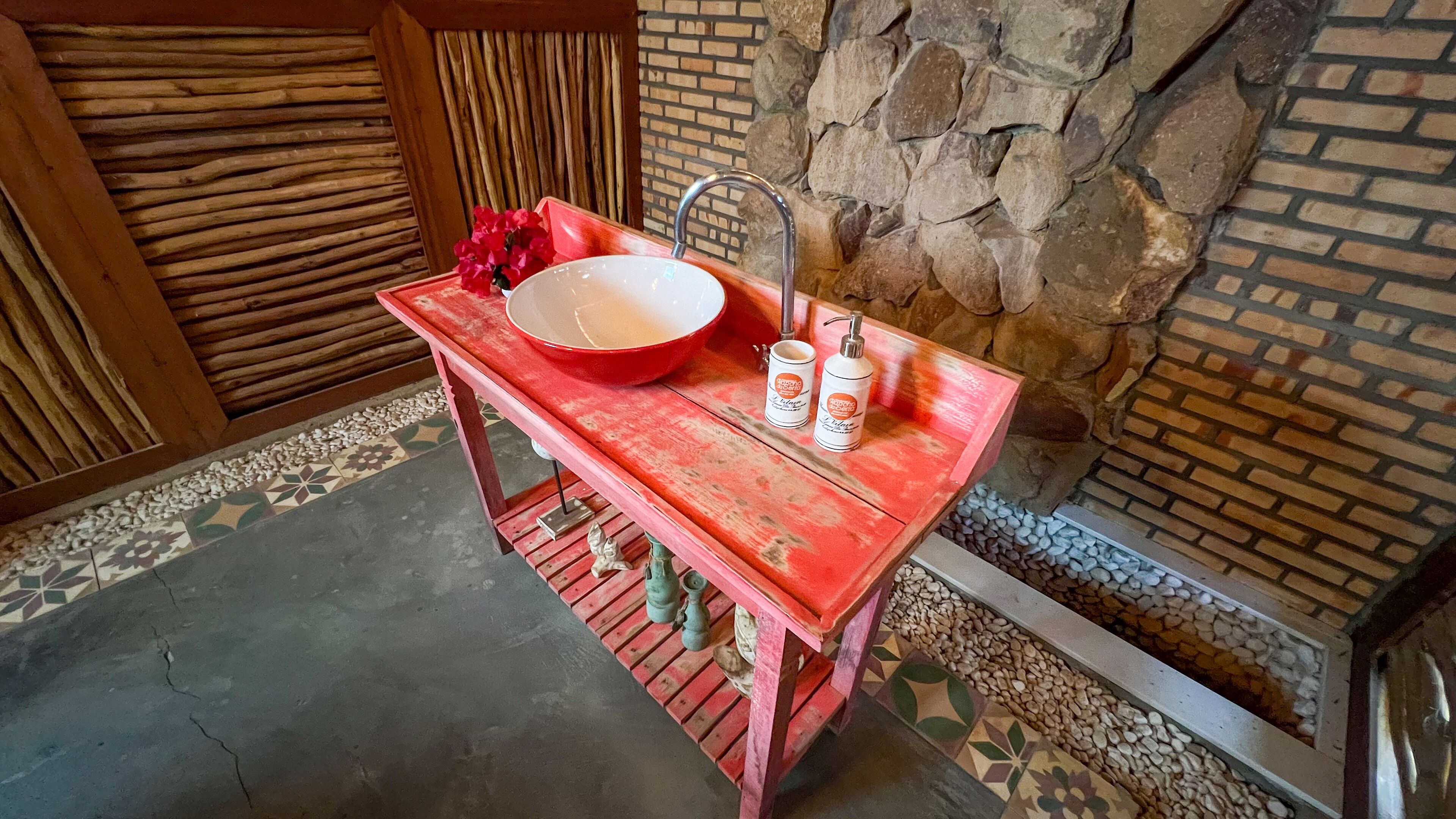 Une table en bois rouge, sur laquelle se trouvent un récipient blanc et deux flacons de lotion.
