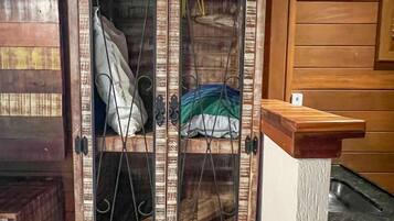 A room with a wooden wardrobe, a small wooden bench, and a white tiled floor.