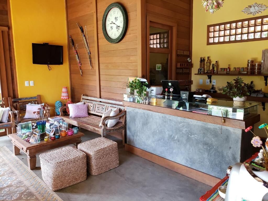A cozy lobby with a wooden reception desk, a large clock, and a television mounted on the wall.