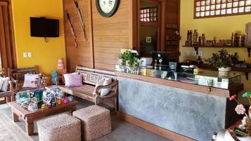 A cozy lobby with a wooden reception desk, a large clock, and a television mounted on the wall.