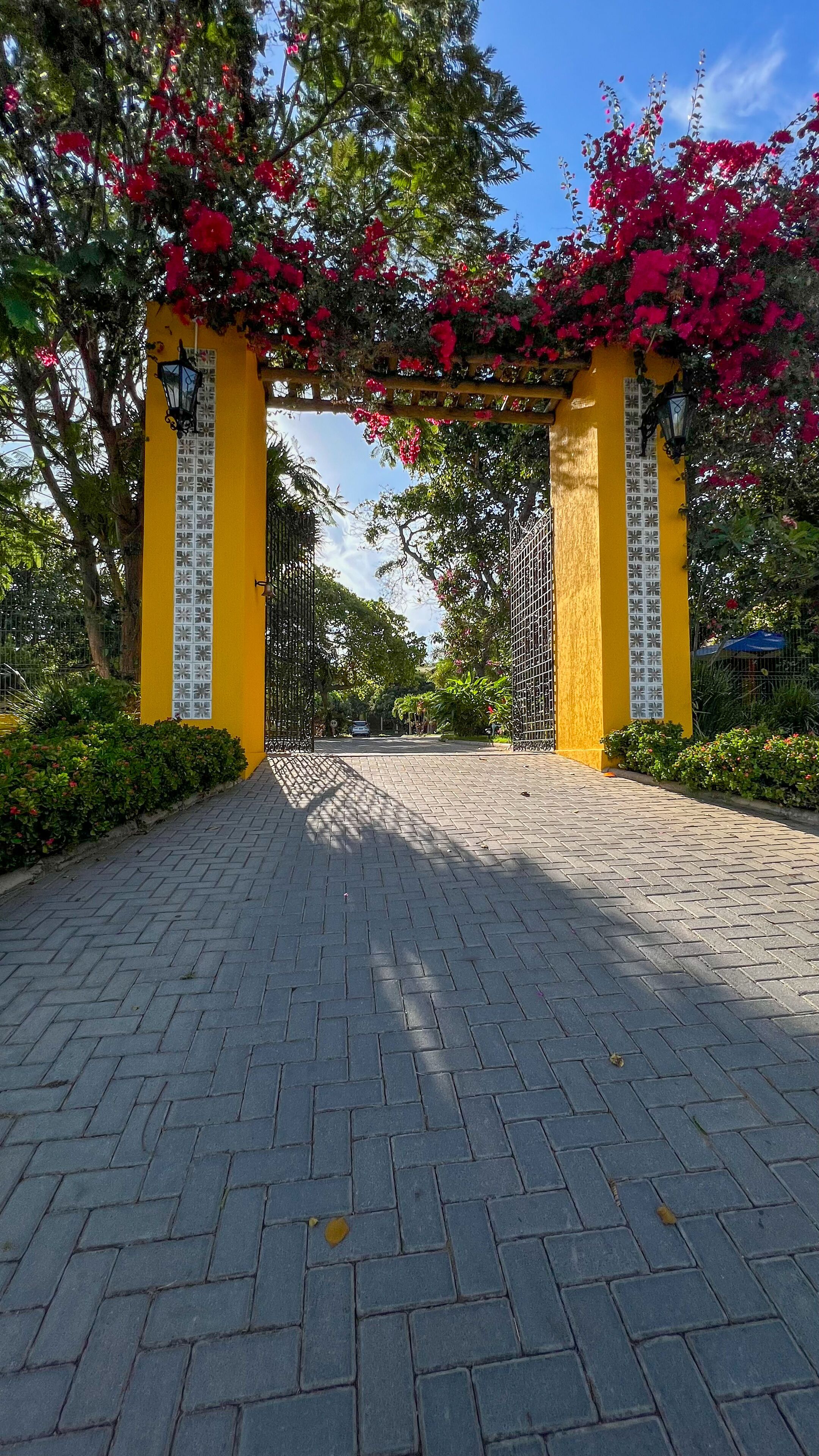 A paved pathway leading to a yellow gate with decorative elements and a clear sky.
