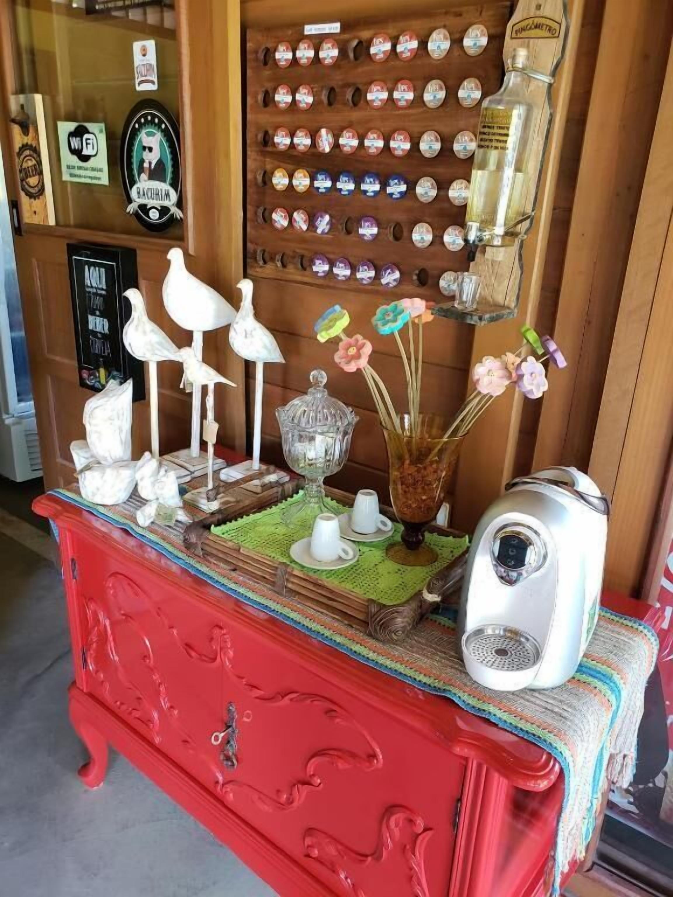 Un armadietto in legno rosso con oggetti decorativi, una parete di bottoni d'epoca e una teiera bianca.
