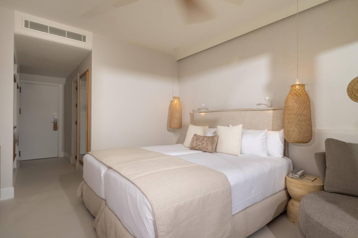 A bedroom with a large bed, bedside tables, and hanging lamps.